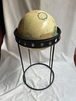 un vieux globe terrestre posé sur un socle, sur fond blanc