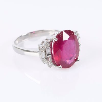 a close up of a ring with a pink stone surrounded by diamonds