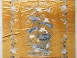 an old chinese embroidered wall hanging with a vase of flowers