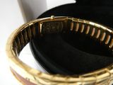 a close up of a gold bracelet with a black case