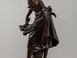 bronze statue of a woman with a basket of flowers on a pedestal