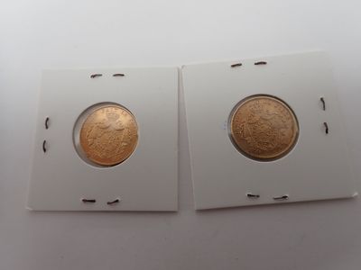 deux pièces d'or dans une boîte blanche posée sur une surface blanche