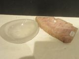 a piece of ham sitting on a plate next to a bowl