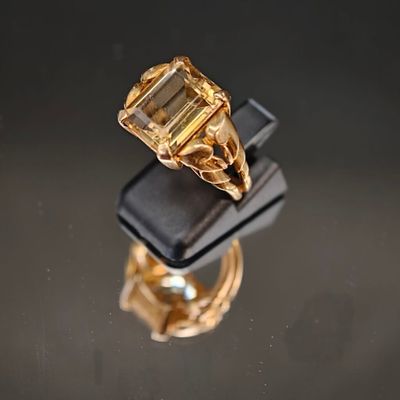 une image représentant une bague en or sertie d'une émeraude, posée sur un écrin noir