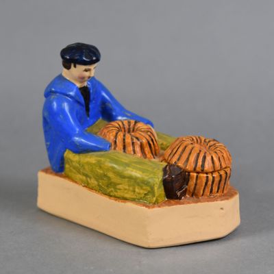 une figurine représentant un homme assis sur un lit avec un chien