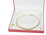 a gold necklace in a red box on a white background