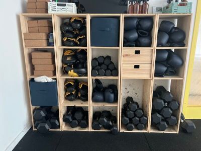 une étagère sur laquelle sont posés plusieurs kettlebells noirs
