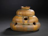 a brown vase with holes in it on a black background