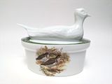 a white duck sitting on top of a white bowl