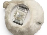 a watch sitting on top of a white fur bag