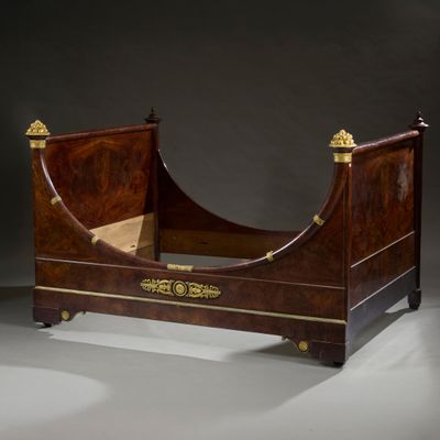 a bed that has a wooden frame with gold decorations on it
