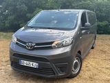 La camionnette grise est garée dans un champ, avec des arbres en arrière-plan.