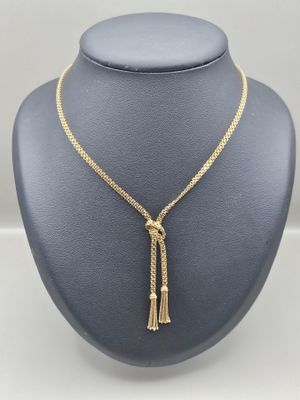 un collier en or orné d'un pompon autour du cou d'un mannequin