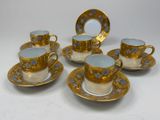 four cups and saucers with gold and blue designs on them