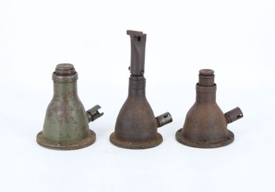 trois vieilles cloches en métal posées les unes à côté des autres sur une surface blanche