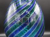 sphère en verre rayée de bleu et de vert, posée sur un socle en acrylique transparent