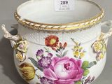 a white vase with flowers on it on a table