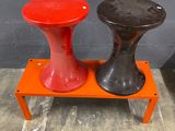 pair of red and black stools sitting on top of a small orange table