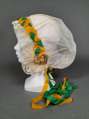 bonnet blanc orné d'un ruban jaune et vert et d'une bordure en dentelle