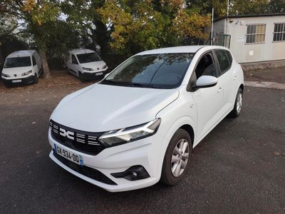 La voiture blanche est garée sur le parking à côté de la maison.