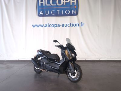 une photo d'un scooter garé devant un panneau « Alcoda Auction »
