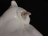 a close up of a white cat statue on a black background