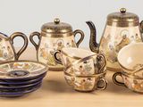 une table sur laquelle se trouvent une théière, des tasses et des soucoupes