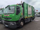 a green garbage truck that is parked in a parking lot