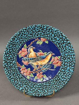 an image of a blue plate with a bird and flowers on it
