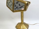 une photo d'une lampe de bureau dorée munie d'un abat-jour en verre