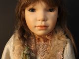 a close up of a doll wearing a dress and a scarf