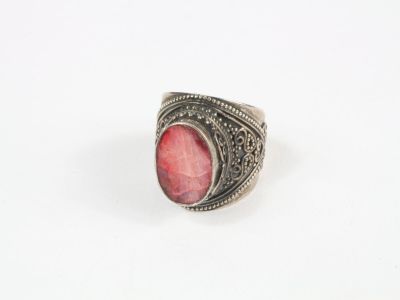 un gros plan d'une bague en argent sertie d'une pierre rouge