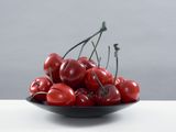 un bol rempli de cerises posé sur une table blanche