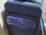 a blue suitcase sitting on the floor next to a cardboard box