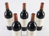 six bottles of wine are lined up on a white surface