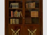 une bibliothèque ancienne à deux portes, ornée de deux épées croisées sur les portes