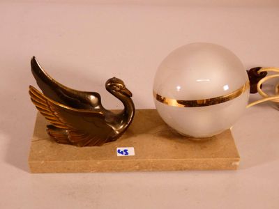 deux figurines de cygnes et une boule posées sur un socle
