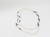 un collier de perles blanches et bleues posé sur une surface blanche