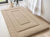 Le tapis de bain est en laine épaisse et présente un poil épais de couleur blanche.