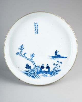 a blue and white plate with a picture of a man on a boat