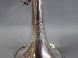 a silver vase with a bird on top of it