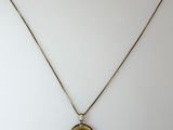 a gold necklace with a coin on a chain