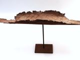 a sculpture of a leaf on a stand on a white surface