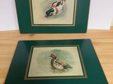 two framed pictures of ducks on a wooden table in a room
