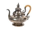 une théière ancienne en argent avec une anse en bois, sur fond blanc