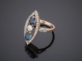 a gold ring with blue and white diamonds on a black surface