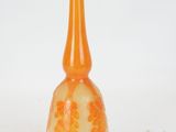 an orange glass vase with flowers on it on a white surface