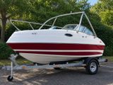 a white and red boat on a trailer in a parking lot