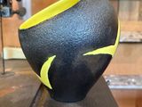 un bol noir et jaune posé sur un morceau de bois