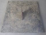 a sundial on the ground with a clock on it